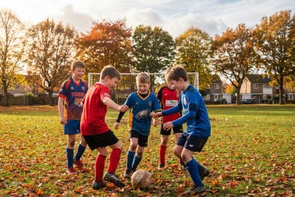 Groupe d'enfants en maillots de football sur un terrain en automne pendant les vacances de la Toussaint